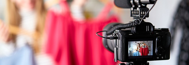 Fashion blogger woman in jeans and turtleneck showing casual colorful shirts on camera. Stylist influencer girl showing trendy clothes filming vlog episode for her channel. Opinion leader sets trends.